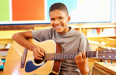 child with a smile holding guitar