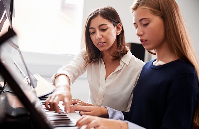 piano teacher and student sitting ata piano
